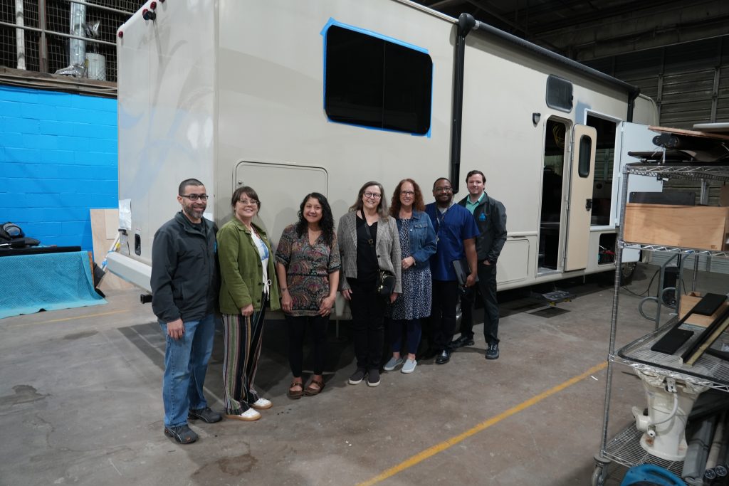 UNC Greensboro School of Nursing faculty and staff members pose for a photo outside the motorhome that will become a mobile health unit.