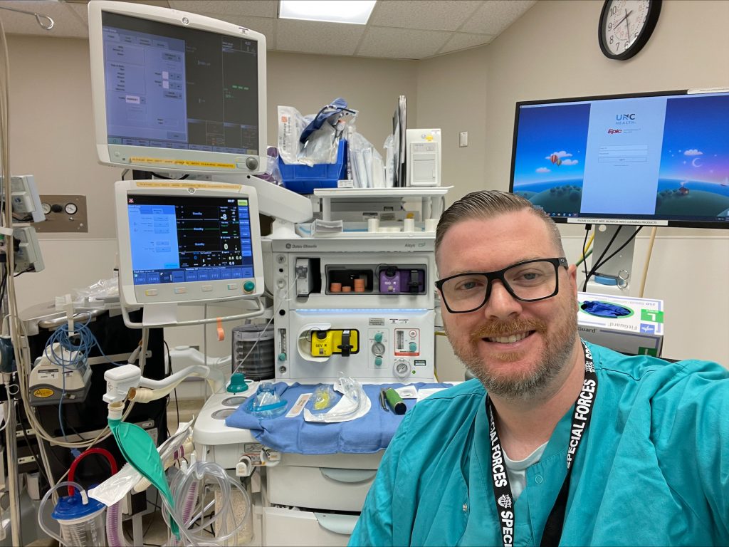 New UNC Greensboro DNP nurse anesthesia graduate Dan Lorden poses with medical equipment.